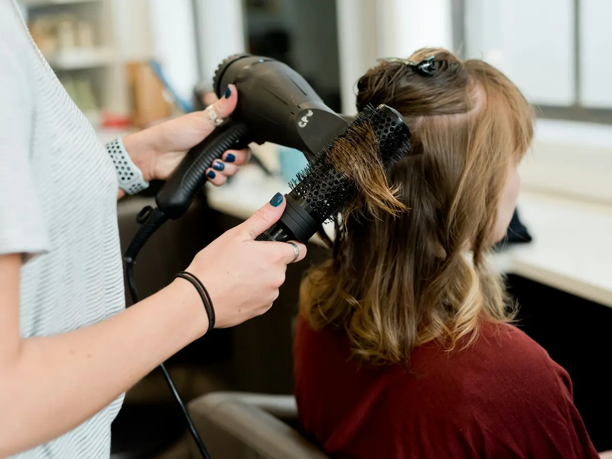 Une coiffeuse fait un brushing à une cliente dans un salon.